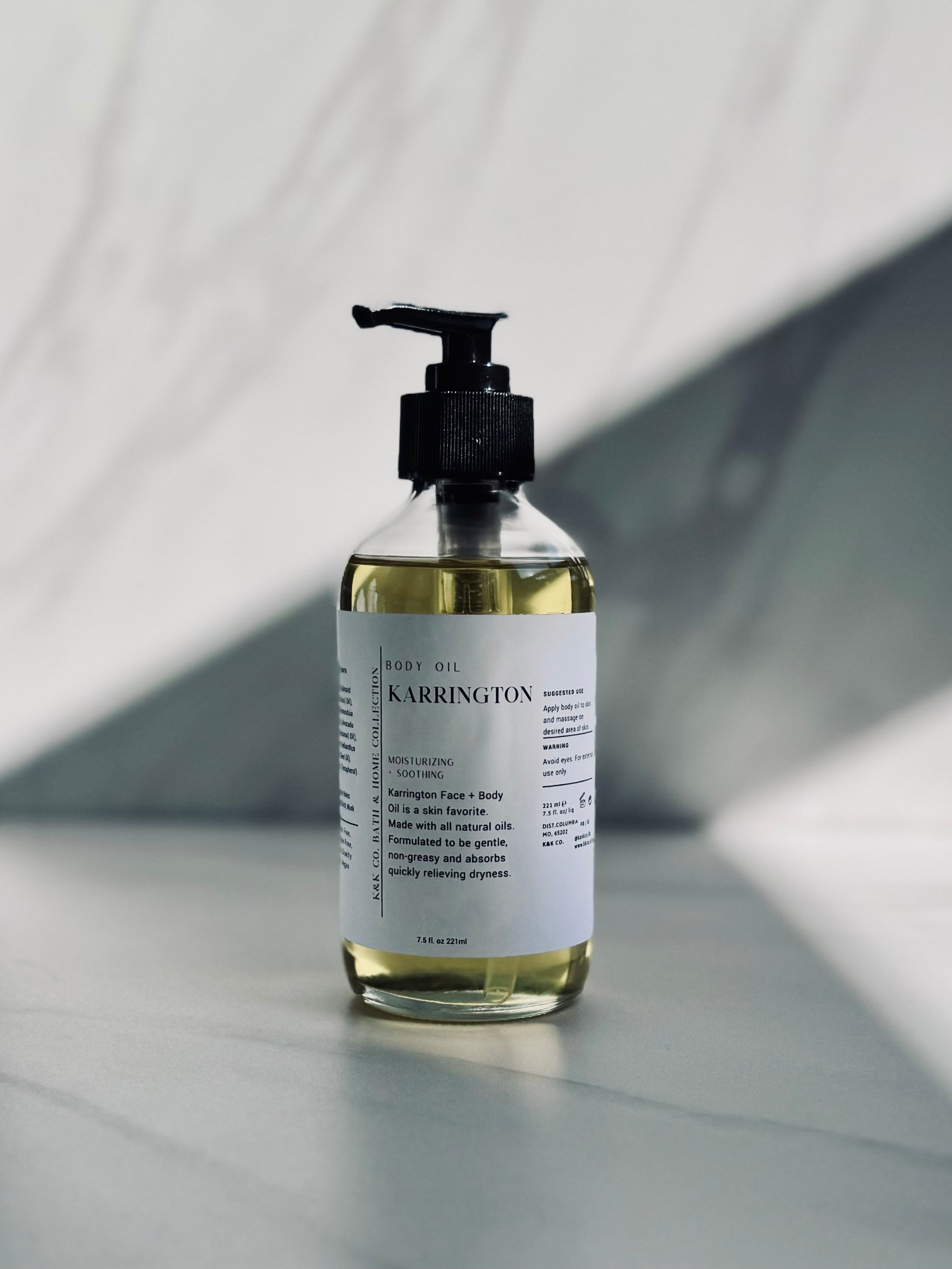 A clear pump bottle containing yellow liquid, labeled Karrington Body Oil.