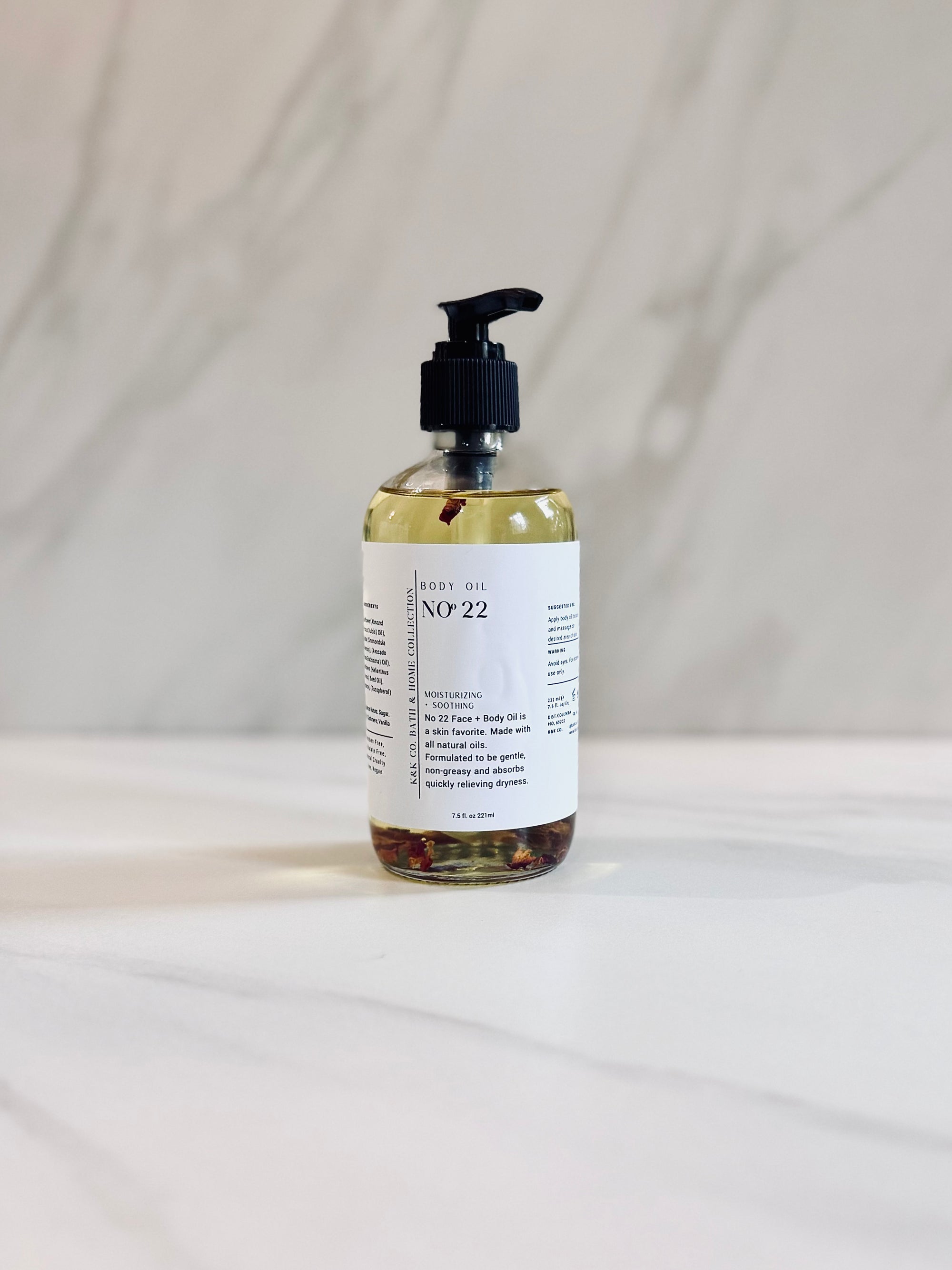 A clear bottle with a pump dispenser containing light yellow body oil. The label reads 'No. 22'.